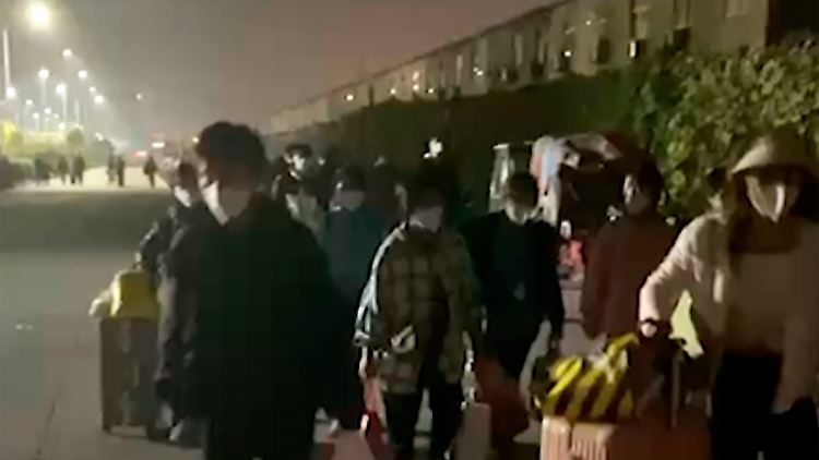 Dieses Videostandbild zeigt Menschen mit Koffern und Taschen, die nach einem Corona-Lockdown das Werksgelände des Apple-Zulieferers Foxconn in Zhengzhou fluchtartig verlassen.