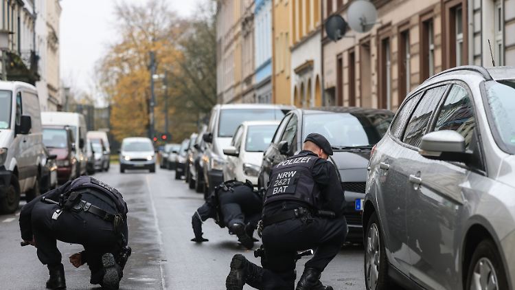 Polizisten suchen in der Nähe eines Tatortes auch unter den geparkten Autos nach weiteren Spuren.
