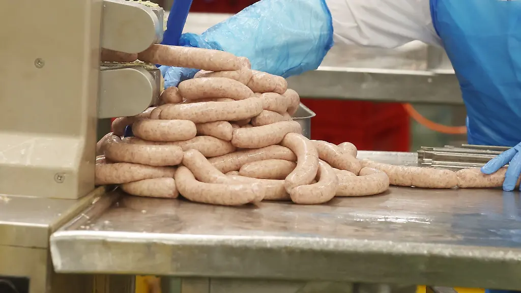 Ein-Mitarbeiter-arbeitet-in-der-Produktion-von-Wurstwaren-in-der-Wolf-Wurstfabrik