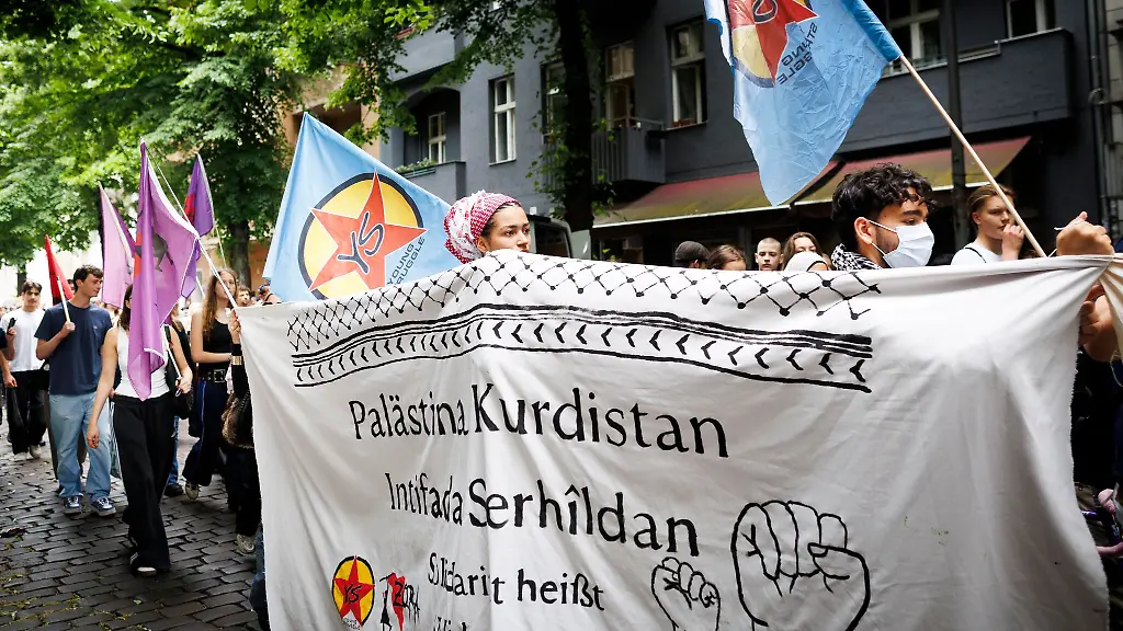 Teilnehmer-gehen-hinter-einem-Transparent-mit-dem-Text-Palaestina-Kurdistan-Intifada-Serhildan-Solidaritaet-heisst-Widerstand-bei-der-Demonstration-Schulstreik-fuer-Palaestina-im-Stadtteil-Neukoelln
