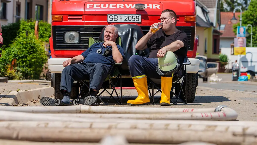 Zwei-Einsatzkraefte-der-Freiwilligen-Feuerwehr-Kleinblittersdorf-machen-Pause-sie-sind-seit-Freitag-ununterbrochen-im-Einsatz