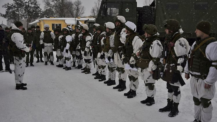 Belarussische Soldaten stehen in winterlicher Landschaft und prüfen ihre Kampfbereitschaft.