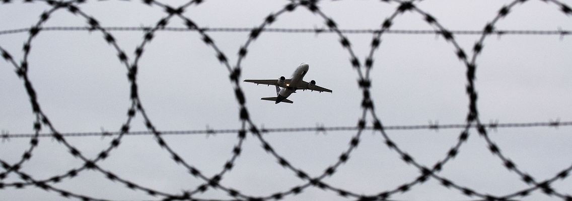Ein Flugzeug fotografiert durch Stacheldraht am Flughafenzaun.