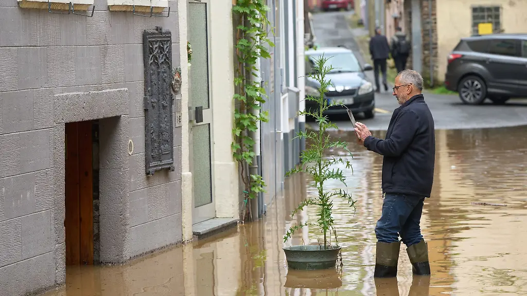 Ein-Mann-fotografiert-ein-Baeumchen-in-einer-Strasse-der-unter-Wasser-stehenden-Altstadt