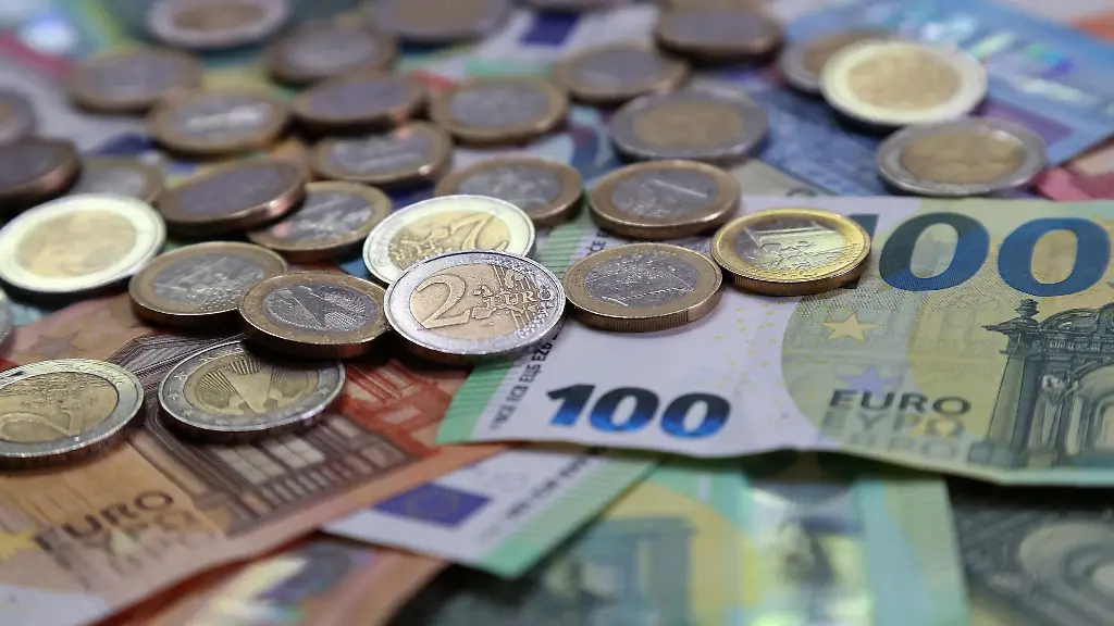 Verschiedene-Euro-Banknoten-und-Euro-Muenzen-liegen-auf-einem-Tisch