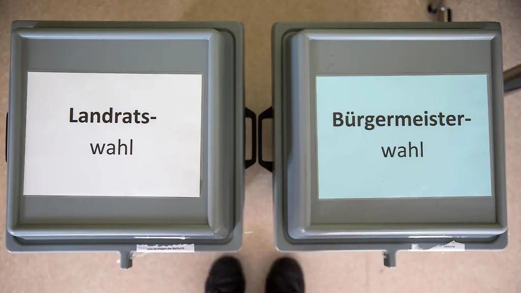 Zettel-mit-der-Aufschrift-Landratswahl-und-Buergermeisterwahl-liegen-auf-den-Wahlurnen-im-Wahllokal