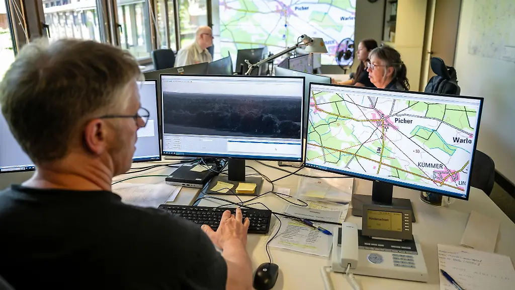 Mitarbeiter-in-der-Waldbrandzentrale-blicken-auf-Monitore-und-werten-Bilder-von-Waldbrandueberwachungskameras-aus