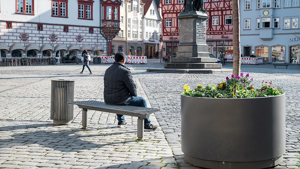 Eine-Person-sitzt-auf-dem-Marktplatz-in-Coburg-auf-einer-Bank-in-der-Sonne