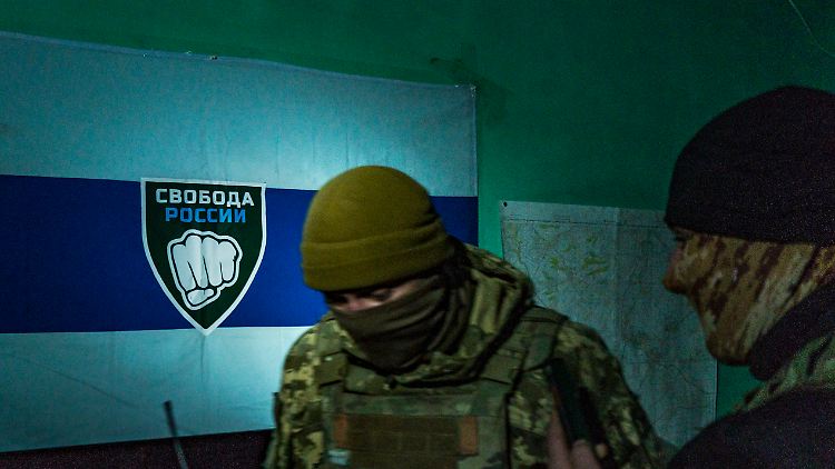 Ein Kämpfer steht vor dem Logo der "Legion Freiheit Russlands".