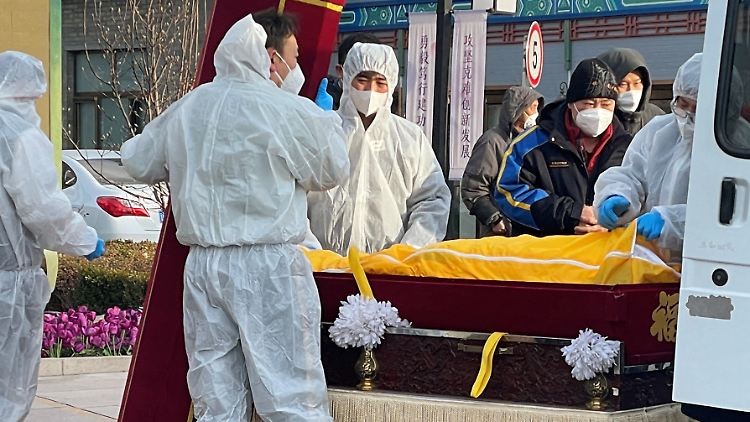 Mitarbeiter eines chinesischen Bestattungsunternehmens verladen einen Sarg.
