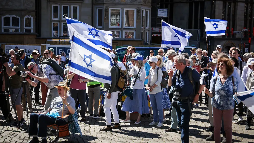 Teilnehmer-einer-Kundgebung-der-deutsch-israelischen-Gesellschaft-Bremen-Unterweser-zum-Unabhaengigkeitstag-des-Staates-Israel-stehen-mit-israelischen-Flaggen-auf-dem-Marktplatz-in-Bremen