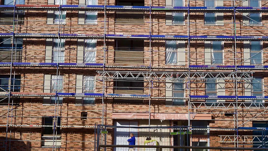 Ein-Bauarbeiter-vor-einem-neuen-Wohnblock-im-Muenchner-Stadtteil-Freiham