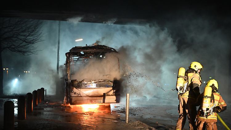 Feuerwehrmänner löschen an der Sonnenallee einen Reisebus, der angezündet worden war.