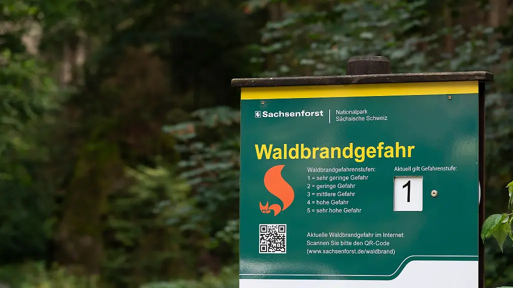 Ein-Hinweisschild-Waldbrandgefahr-zur-aktuellen-Waldbrandwarnstufe-steht-am-Eingang-zu-einem-Wanderweg-im-Nationalpark-Saechsische-Schweiz