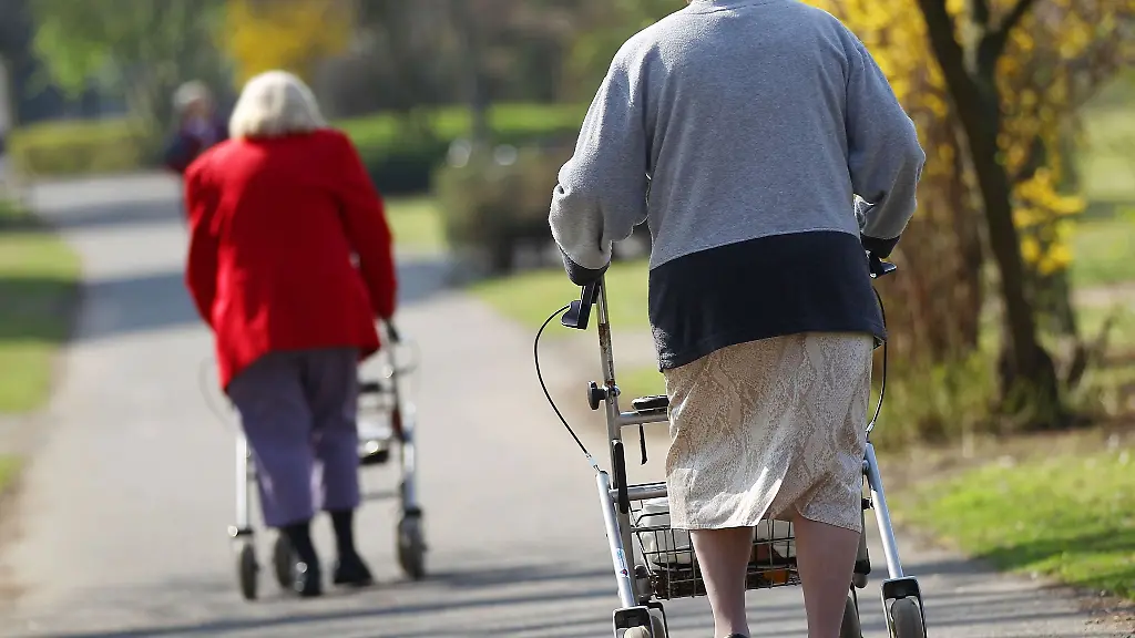 Seniorinnen-mit-Rollator-gehen-durch-den-Park-eines-Altenwohnheimes