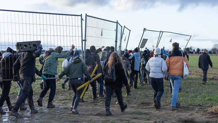 Aktivisten in Lützerath klauen Absperrgitter, um daraus Barrikaden zu bauen.