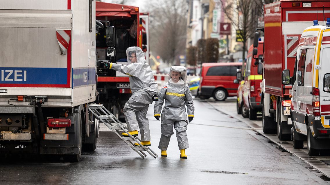 Spezialkräfte der Polizei in Schutzanzügen kommen von ihrem Einsatz.