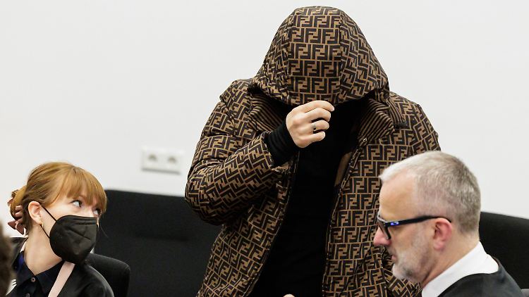 Ein Angeklagter bedeckt neben seinen Anwälten sein Gesicht mit einer Kapuze im Gerichtssaal des Oberlandesgerichts Dresden.