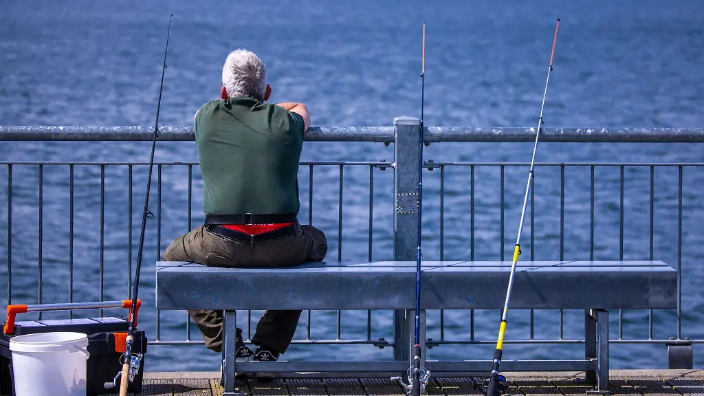 Ein-Angler-sitzt-auf-der-Seebruecke-an-der-Ostseekueste