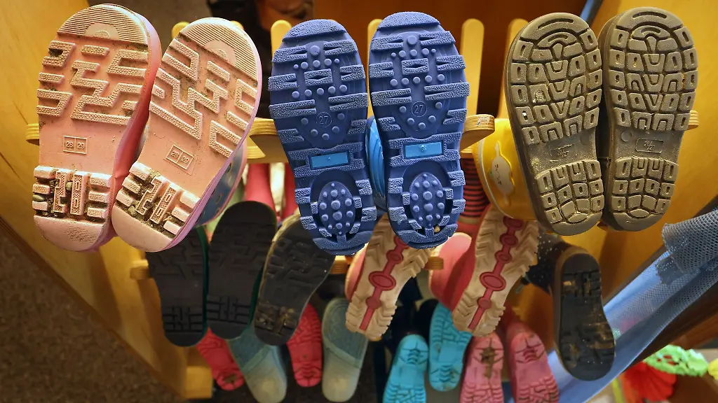 Gummistiefel-von-Kindern-sind-an-einem-Gestell-aufgereiht