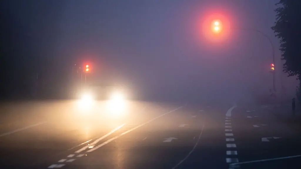 Die-Lichter-eines-Autos-und-einer-Ampelanlage-leuchten-aus-dem-Morgennebel