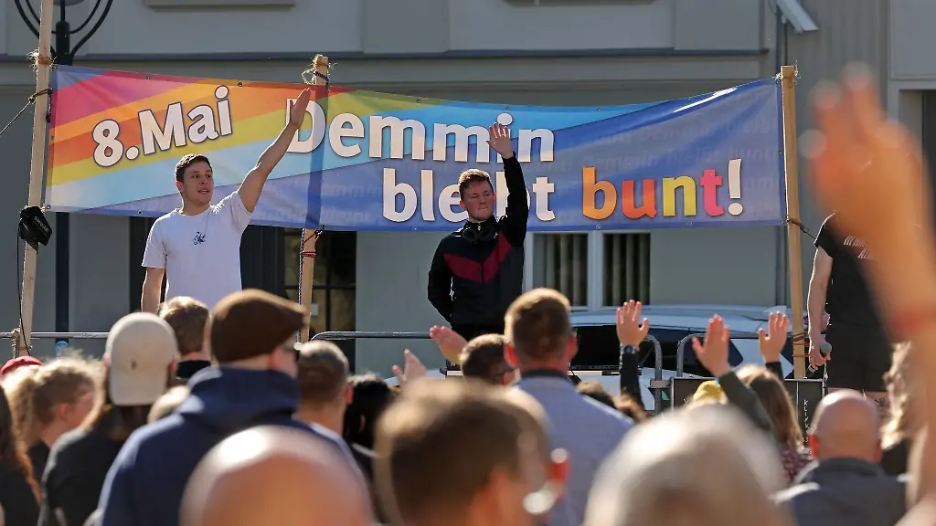 Auf-dem-Marktplatz-haben-sich-Besucher-beim-Friedensfest-gegen-einen-Aufmarsch-von-Rechtsextremen-eingefunden-auf-einem-Transparent-steht-8-Mai-Demmin-bleibt-bunt