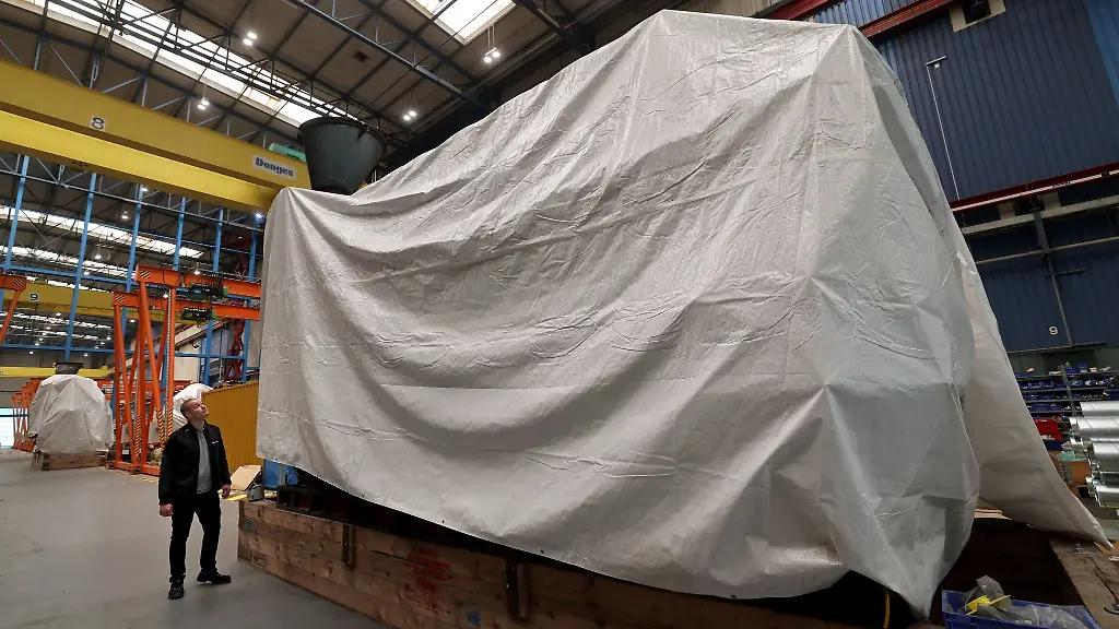 Benjamin-Illgen-Projektleiter-am-neuen-Anwendungszentrum-Wasserstoff-des-Fraunhofer-Instituts-fuer-Grossstrukturen-in-der-Produktion-IGP-steht-bei-einem-Pressetermin-neben-einem-der-abgedeckten-Schiffsmotoren