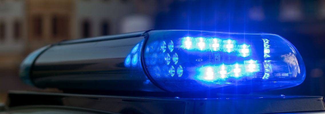 Das Blaulicht auf einem Fahrzeug der Polizei leuchtet in der Dunkelheit.