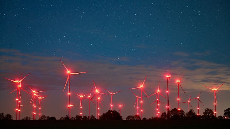 Rote Positionslichter an Windenergieanlagen erhellen den Nachthimmel und die Landschaft bei Jacobsdorf in Brandenburg.
