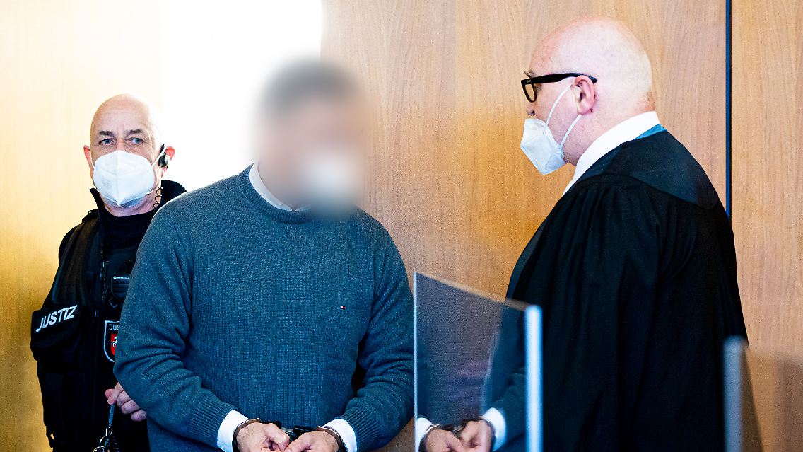 Der Angeklagte steht neben seinem Verteidiger in einem Saal vom Landgericht Hildesheim.