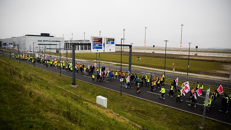 Der Zug einer Demonstration zum Warnstreik am Flughafen Berlin-Brandenburg BER zieht vorbei an Terminal 2 in Richtung Terminal 1.