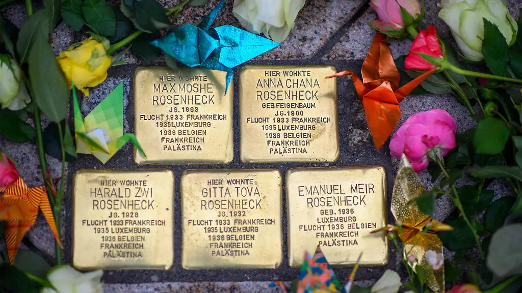 Blumen-und-Papierkraniche-liegen-um-die-Stolpersteine-die-dort-der-Familie-Rosenheck-gedenken