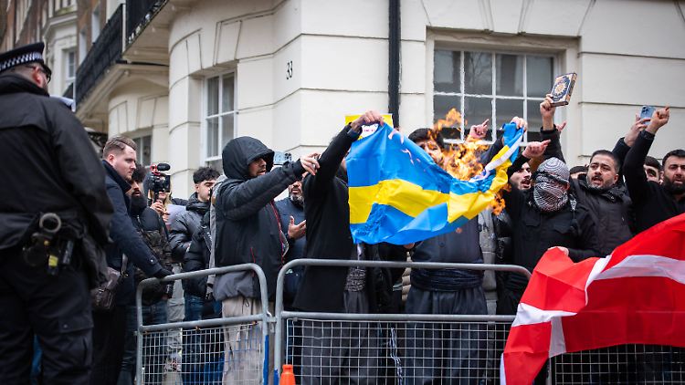 Menschen entzünden die schwedische Flagge bei einer Demonstration gegen die Koranverbrennungen in London. 