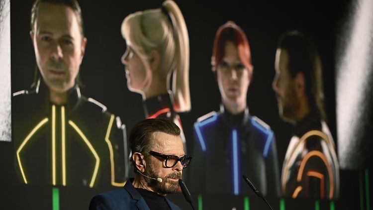 Björn Ulvaeus gibt eine Pressekonferenz, im Hintergrund sind die digitalen Konterfeis von ihm und seinen ABBA-Bandkollegen. 