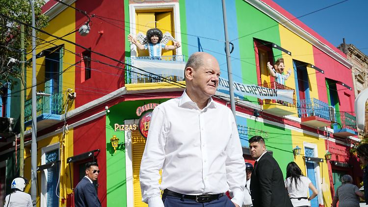 Der Bundeskanzler Olaf Scholz, im Hintergrund eine Maradona-Figur.