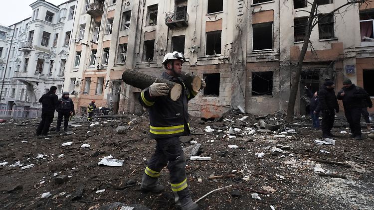 Eine Rettungskraft trägt Teile eines abgesägten Baumes, nach der russischen Attacke auf Charkiw.