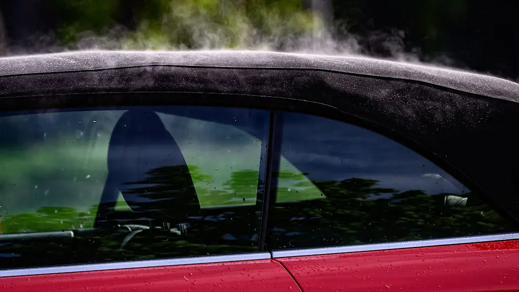 Das-Faltdach-eines-roten-Cabriolet-dampft-am-Vormittag-auf-einem-Parkplatz-in-der-Innenstadt