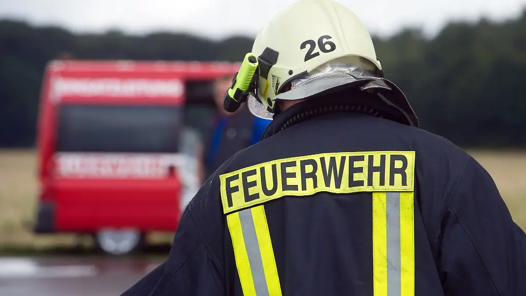 Ein-Feuerwehrmann-steht-vor-einem-Einsatzfahrzeug