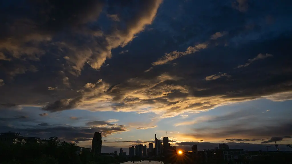 Dunkle-Wolken-ziehen-im-letzten-Tageslicht-ueber-die-Skyline-von-Frankfurt-am-Main-hinweg-waehrend-die-Sonne-neben-den-Banken-untergeht-Das-Wetter-bleibt-zunaechst-kalt-und-wechselhaft