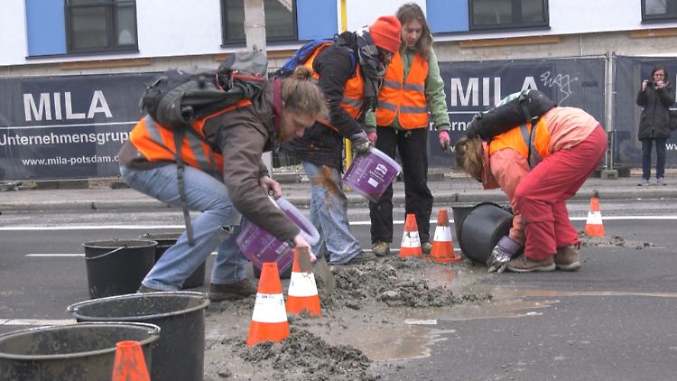 Klima-Aktivisten schütten Beton auf die Straße.