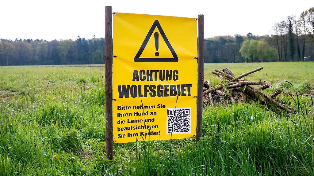Ein-Schild-mit-der-Aufschrift-Achtung-Wolfsgebiet-steht-auf-einem-Feld