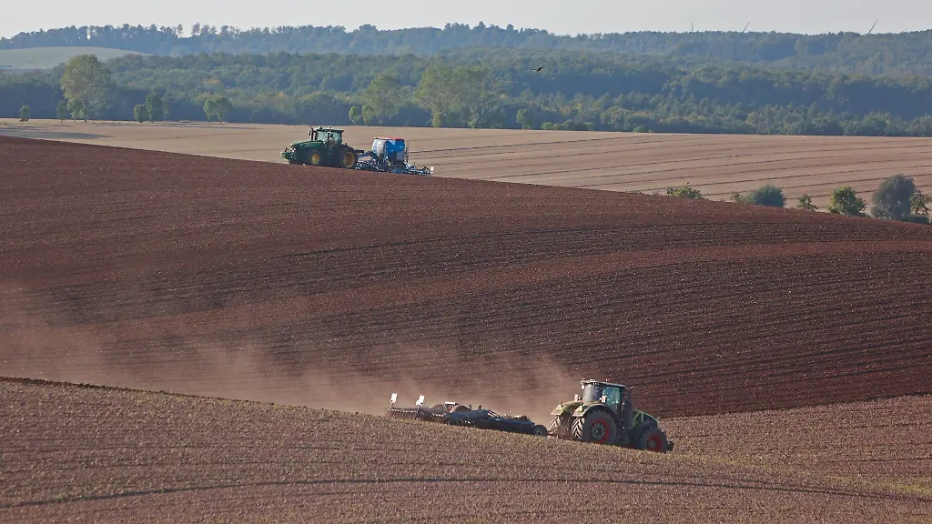 Ein-Landwirt-faehrt-mit-einem-Traktor-ueber-ein-Feld-und-lockert-den-Boden-auf