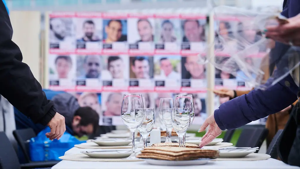 Mitglieder-unterschiedlicher-Initiativen-decken-einen-Tisch-dessen-zwoelf-Stuehle-leer-bleiben-die-an-die-verschleppten-Geiseln-der-Hamas-erinnern-sollen