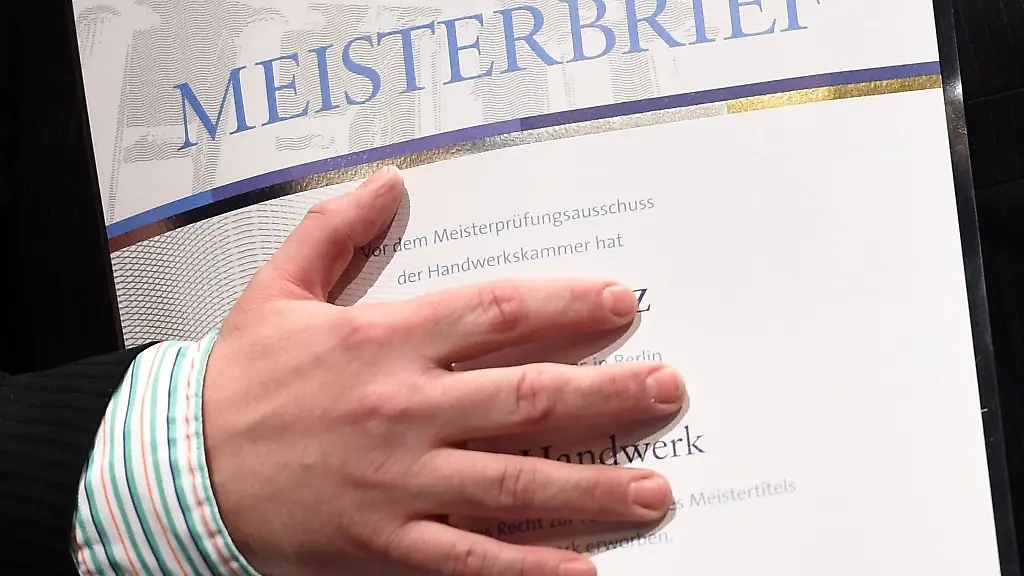 Ein-junger-Mann-freut-sich-bei-der-Meisterfeier-ueber-seinen-Meisterbrief