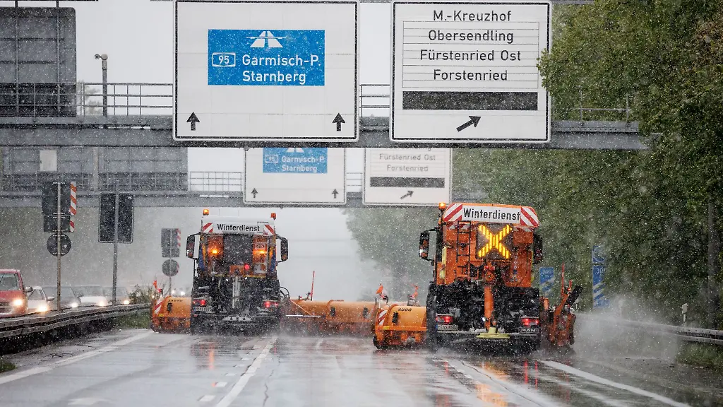 Zwei-Fahrzeuge-vom-Winterdienst-fahren-bei-Schneefall-ueber-die-Autobahn-95-in-Muenchen