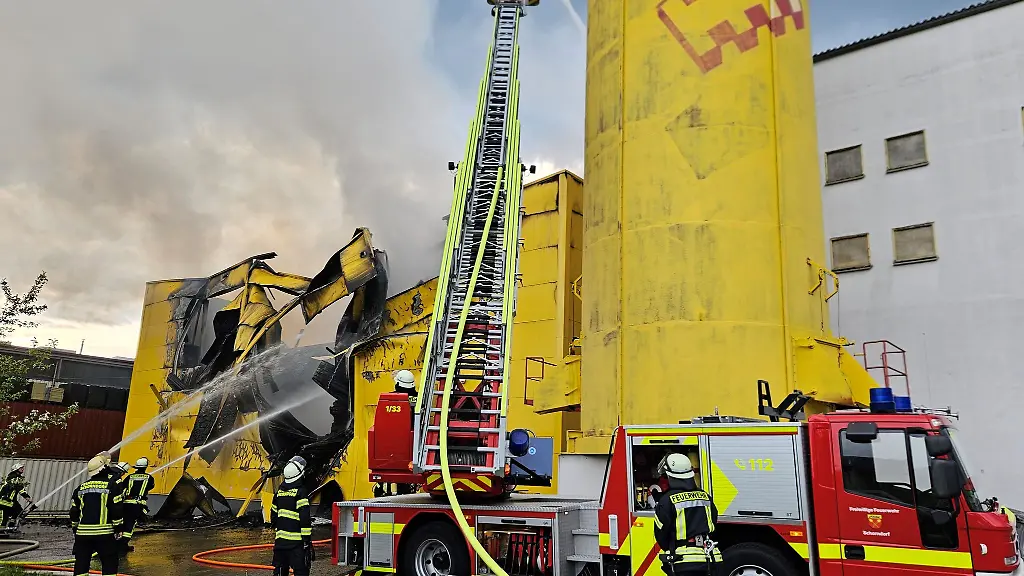 Einsaetzkraefte-der-Feuerwehr-loeschen-eine-in-Brand-geratene-Lagerhalle