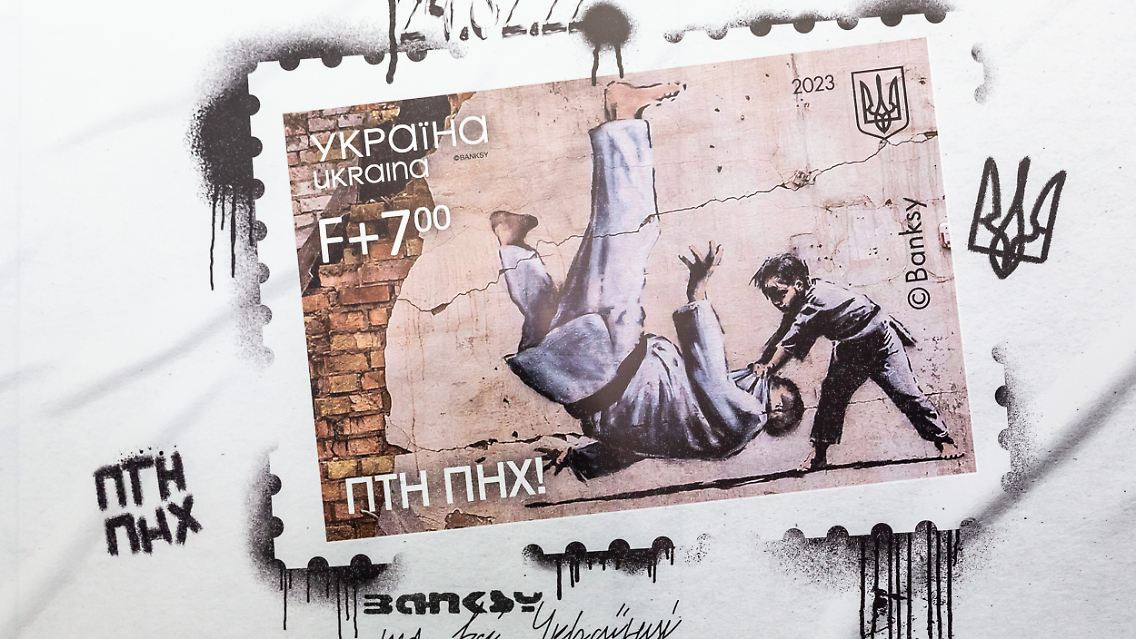Das Bild ist vom russischen Präsidenten Wladimir Putin inspiriert, der bekanntlich den schwarzen Gürtel im Judo trägt, und zeigt einen jungen Judoka, der die Ukraine repräsentiert und einen erwachsenen Mann niederschlägt.