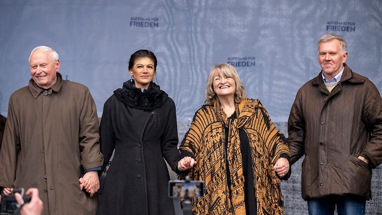 Sahra Wagenknecht neben ihrem Mann Oskar Lafontaine auf der Bühne am Brandenburger Tor, daneben Alice Schwarzer und Ex-General Erich Vad, der ebenfalls eine Rede hielt.