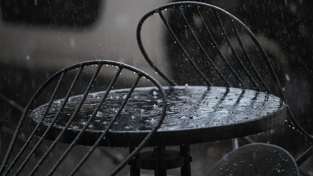 Hagel-und-Regen-prasselt-auf-einen-Tisch-eines-Cafes-im-Aussenbereich