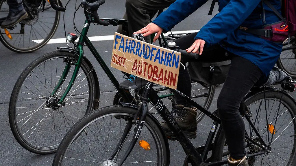 Bei-einer-Demo-faehrt-ein-Fahrradfahrer-mit-einem-Schild-mit-der-Aufschrift-Fahrradfahr-n-statt-Autobahn
